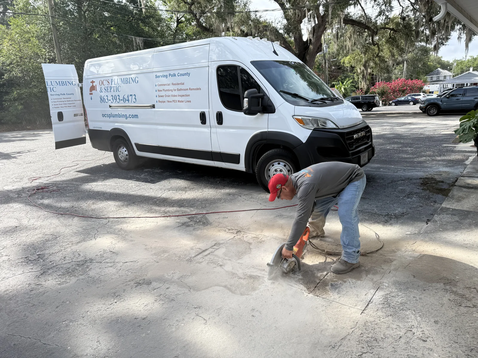 OC's Plumbing & Septic technician completing concrete access work beside a branded service van
